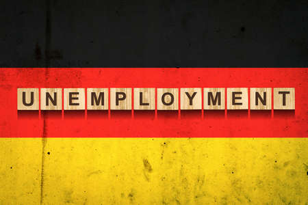 Unemployment. The inscription on wooden blocks on the background of the German flag. Unemployment growth. Business. Job.の写真素材