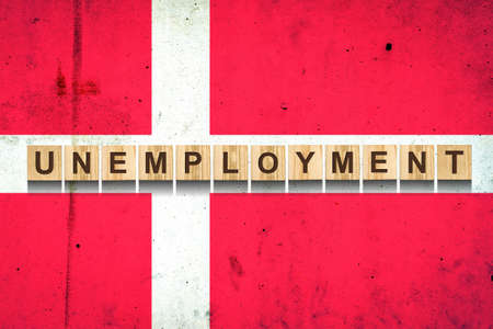 Unemployment. The inscription on wooden blocks on the background of the Denmark flag. Unemployment growth. Business. Job.の写真素材
