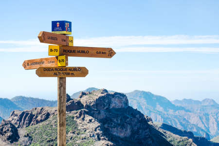 Grand Canaria. Spain. December. 4, 2018. Wooden sign of mountain routes. Against the blue sky and the beautiful mountains. Tourism. Travelsのeditorial素材
