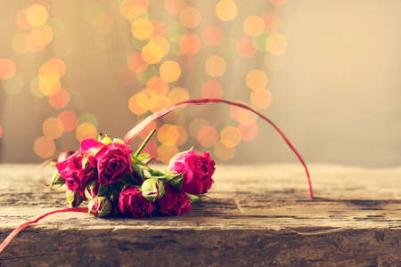 A gift with roses on a wooden table. Greeting card on March 8, mother's day. Copy space. Bokeの写真素材
