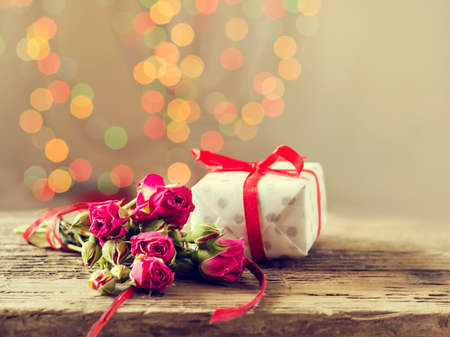 A gift with roses on a wooden table. Greeting card on March 8, mother's day. Copy space. Bokeの写真素材