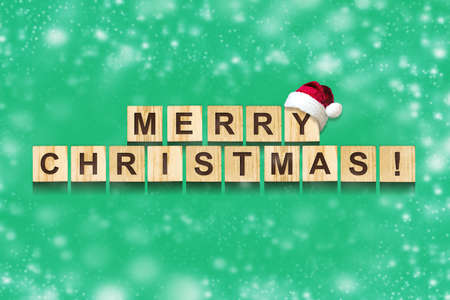 Merry Christmas, Inscription on wooden blocks, on a green background. Snow effect. Christmas...