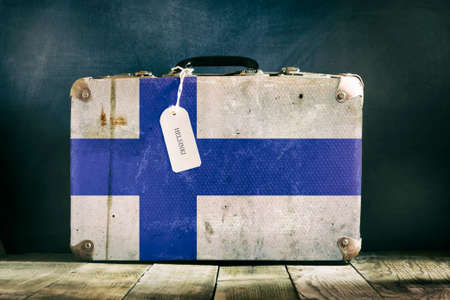 Old suitcase with the Finland flag on wooden background. Travelsの写真素材