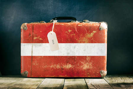 Old suitcase with the Latvia flag on wooden background. Travelsの写真素材
