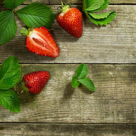 Two and a one half strawberrys on a old wooden backgroundの写真素材