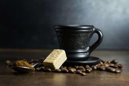 Cup of hot coffee with spoon and candy on wooden backgroundの写真素材