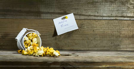 White bucket with popcorn on wooden background