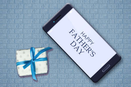 Happy father's day background. Smartphone and gift on the background of many inscriptions Happy...
