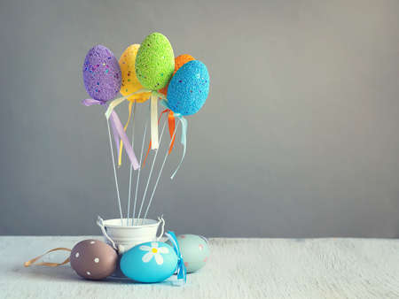 Multicolored easter eggs on sticks in small white bucket. The inscription of Happy Easter. Copy...