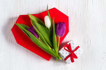 Beautiful tulips on a red heart. White wooden background. Mother's Day. Happy Women's Day. Greeting card.の写真素材