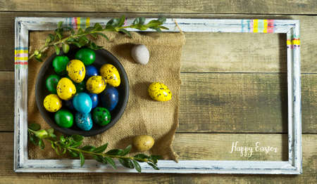 Easter colored eggs in a bowl on a wooden background with copy space