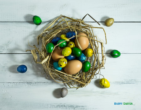 Easter colorfull eggs in a nest on a white wooden background with copy spaceの写真素材