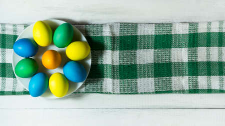 Colorful Easter eggs in a white plate. Top view with copy space