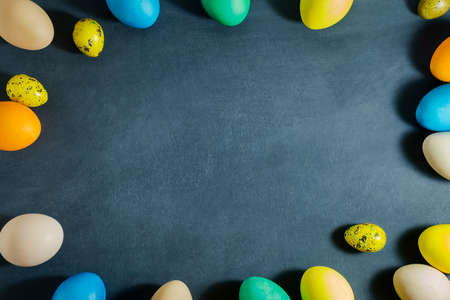 Easter composition with colorful eggs on a dark blue background.Top view with copy space