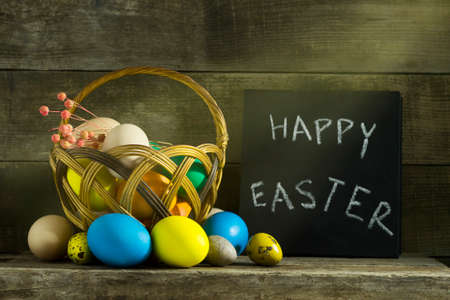 Easter still life with colorful eggs on an old wooden background. With the inscription of the Happy...
