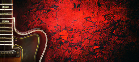Old, jazz electric guitar on a red grunge background. Copy space. Background for music festivals,...