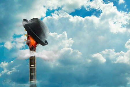 An old electric guitar, and a hat, in a cloudy sky. Background for festivals, concerts. Copy space....