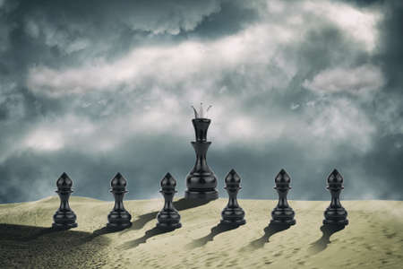Pawns and black chess queen in the sand dunes. cloudy sky. leadership concept. success. abstraction. business. background.の写真素材