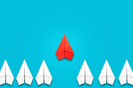 Red paper plane flying in front of a group of whites. blue background. copyspace. Leadership concept, teamwork, personnel management. business. lifestyle. background.の写真素材