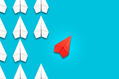 Red paper plane flying in a different direction than the white ones. blue background. copyspace. The concept of innovative solutions, creativity. business. lifestyle. background.の写真素材