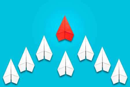 Red paper plane flying in front of a group of whites. blue background. copyspace. Leadership concept, teamwork, personnel management. business. lifestyle. background.の写真素材