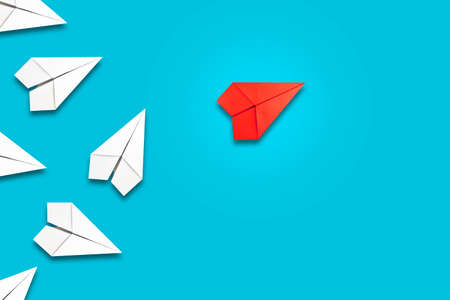 Red paper plane flying in front of a group of whites. blue background. copyspace. Leadership concept, teamwork, personnel management. business. lifestyle. background.の写真素材