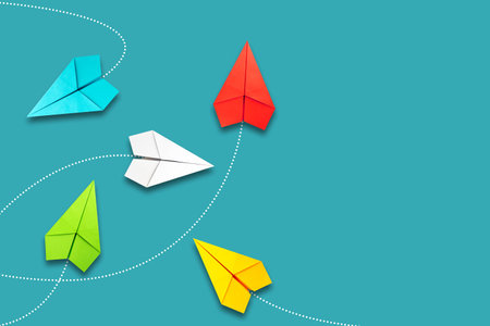 Red paper plane flying in a different direction than multicolored. blue background. copyspace. The concept of innovative solutions, creativity. business. lifestyle. background.の写真素材