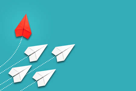 Red paper plane flying in a different direction than the white ones. blue background. copyspace. The concept of innovative solutions, creativity. business. lifestyle. background.の写真素材