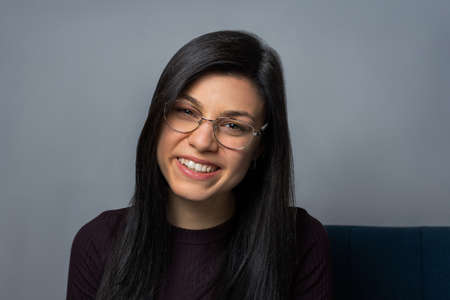 Portrait of a beautiful smiling young brunette woman wearing glasses. people. lifestyle. gray background.の写真素材