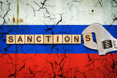 sanctions. Word on wooden blocks. Against the background of the flag of Russia.Wrench. business. politics. Economyの写真素材