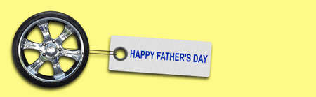 Happy Father's Day. Words on the tag, and auto wheel In a yellow background. copyspace. holidays. background.の写真素材