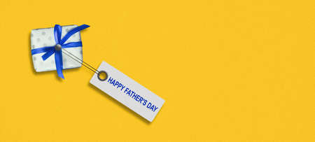 Happy Father's Day. Words on the tag, and a gift on a yellow background. copyspace. holidays. background.の写真素材