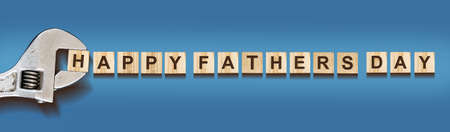 Happy Father's Day words on wooden blocks. Wrench. On a blue background. Festive banner. holidays. Congratulations.の写真素材