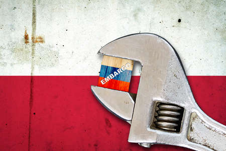 embargo. Word on a wooden block in the colors of the Russian flag. Clamped-wrench. Against the background of the flag of Poland. business. politics. Economyの写真素材