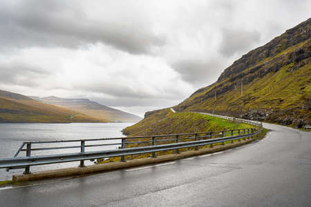 Road near the beautiful mountains, and the sea bay. Faroe Islands. Denmark, Europe. landscapes. Nature. travel concept backgroundの写真素材