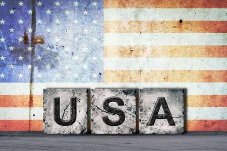USA, words on stone blocks, on grunge background of America flag, on a concrete wall. copyspace. Signs and symbols.Countries.の写真素材
