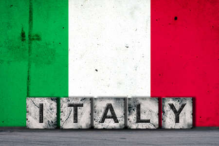 Italy, words on stone blocks, on grunge background of Italy flag, on a concrete wall. copyspace. Signs and symbols.Countries.の写真素材