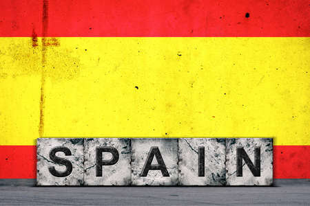 Spain, words on stone blocks, on grunge background of Spain flag, on a concrete wall. copyspace. Signs and symbols.Countries.の写真素材