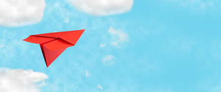 Red paper plane in the blue cloudy sky. The concept of rest, plans, and goals. copy space. Lifestyle. Business.の写真素材