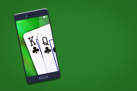 Playing cards on the smartphone screen. Green background. copy space. Online casino concept. Gambling. Background.の写真素材