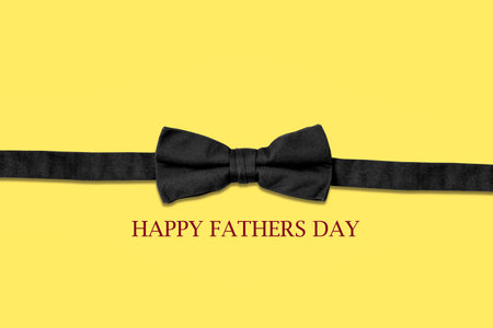 Happy Fathers Day. Black Bow Tie, and words on a yellow background. Copy space. Fathers Day Concept....