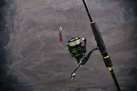 Spinning rod with reel on a dark background. Copy space. Fishing background.