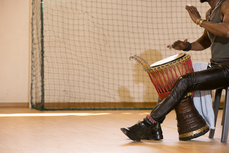 African man, leather pants, playing drum, bracelets