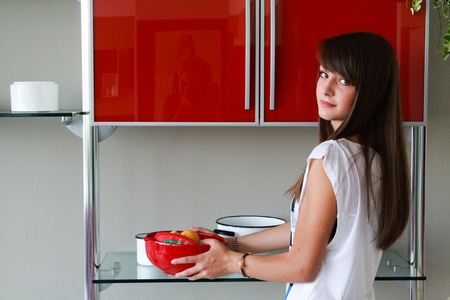 young woman in modern kitchen holding red bowl of fruitの写真素材
