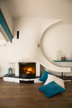 Modern style home with lit on fireplace, wooden floors and teal accessoriesの写真素材