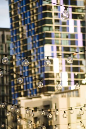 A hanging string of lights at Queen Victoria Markets with the skyline of Melbourne city in the backgroundの写真素材