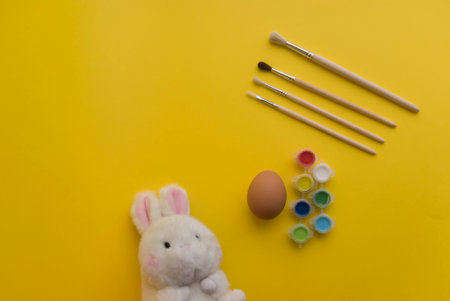 Easter bunny, easter eggs and brushes on a yellow backgroundの写真素材