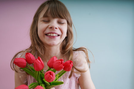 Little girl with a bouquet of tulips on a pink backgroundの写真素材