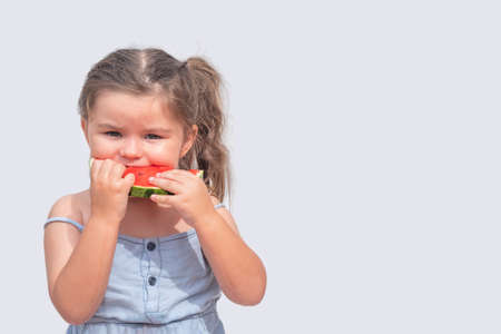 Cute girl 3 years old eats a red watermelon on a white background