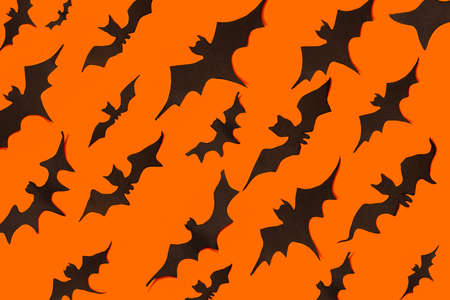 decoration concept for Halloween. Black paper bats fly in one directions on an orange background....